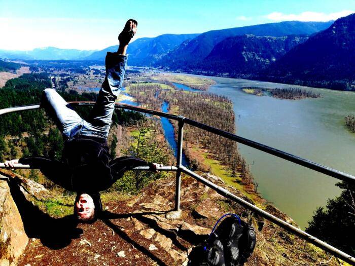 Adam Overby hanging upside down on a rail at the end of a hike near hood river in Skamania Washington
